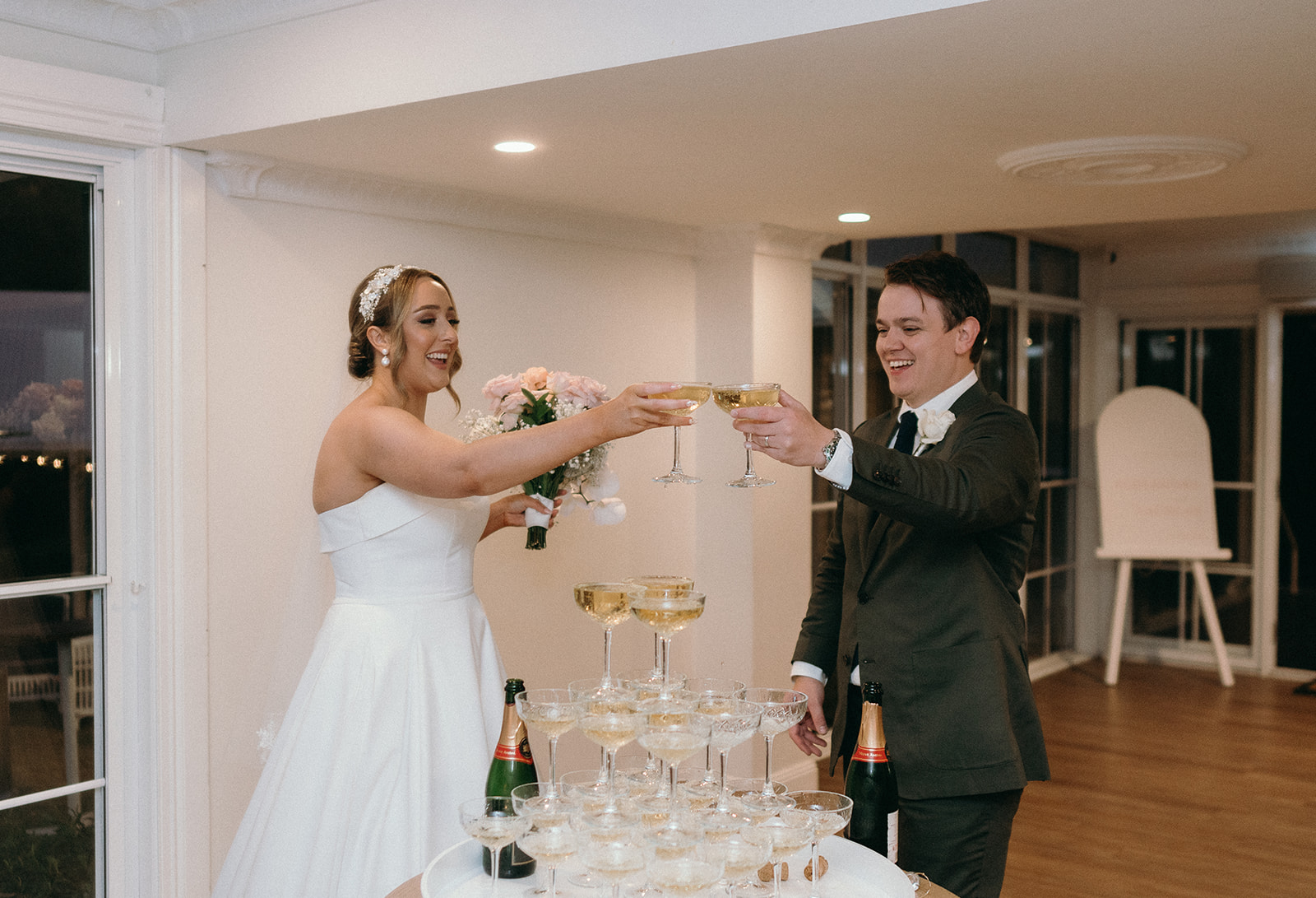 Couple married at Maleny Manor doing cheers after their champagne tower